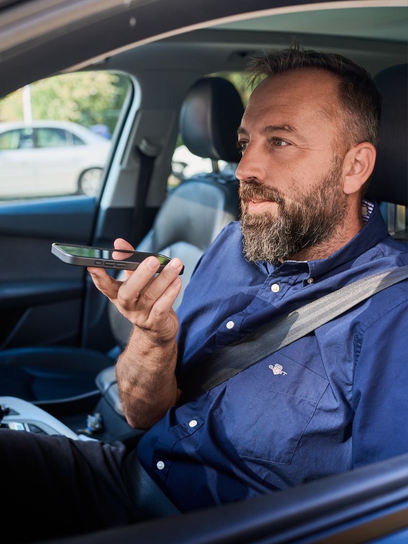 Muž v autě diktuje záznam do telefonu